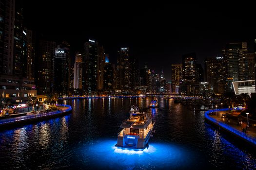 Captivating nightscape of Dubai Marina skyline with illuminated yachts and skyscrapers.