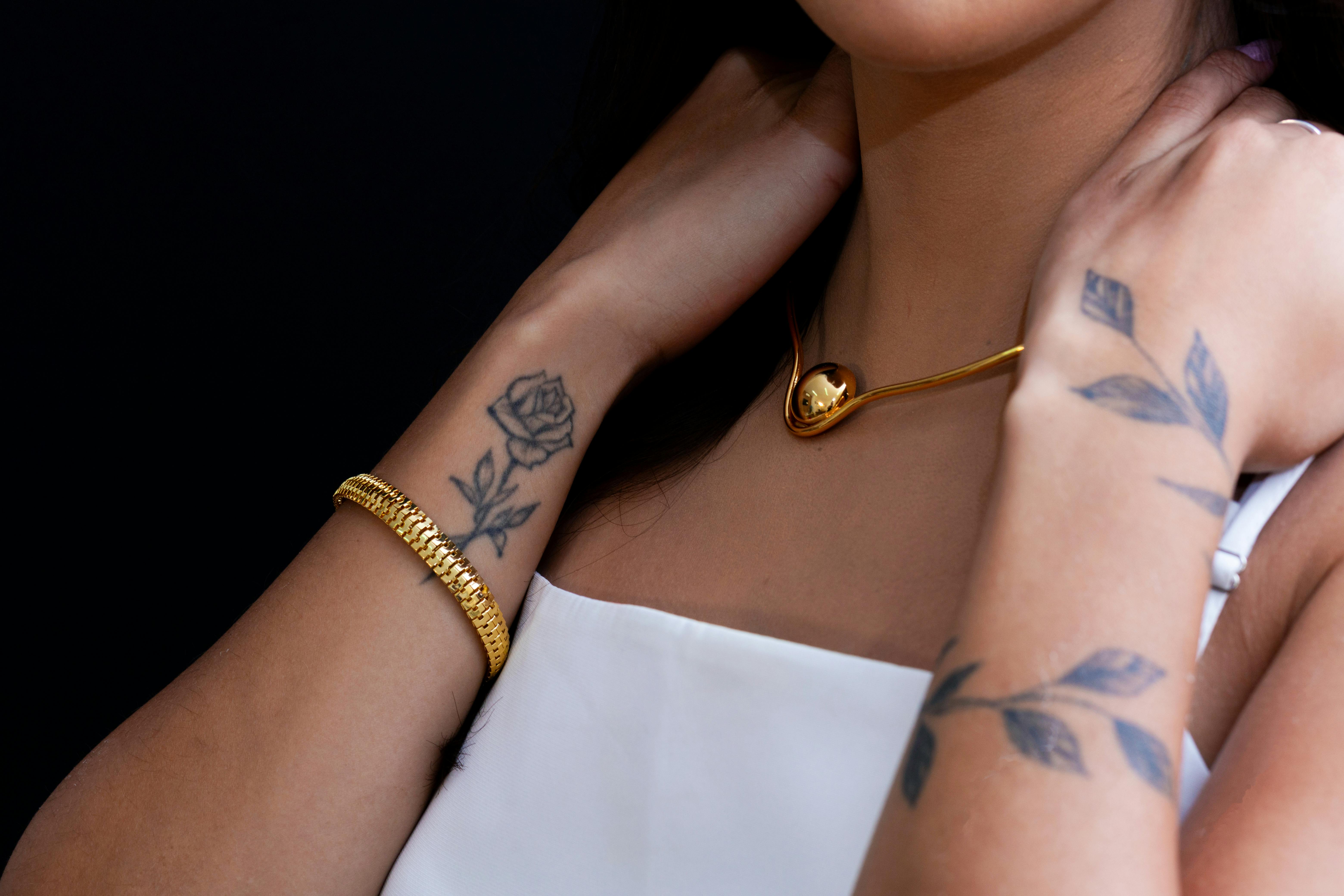 close up of tattooed arms with gold jewelry