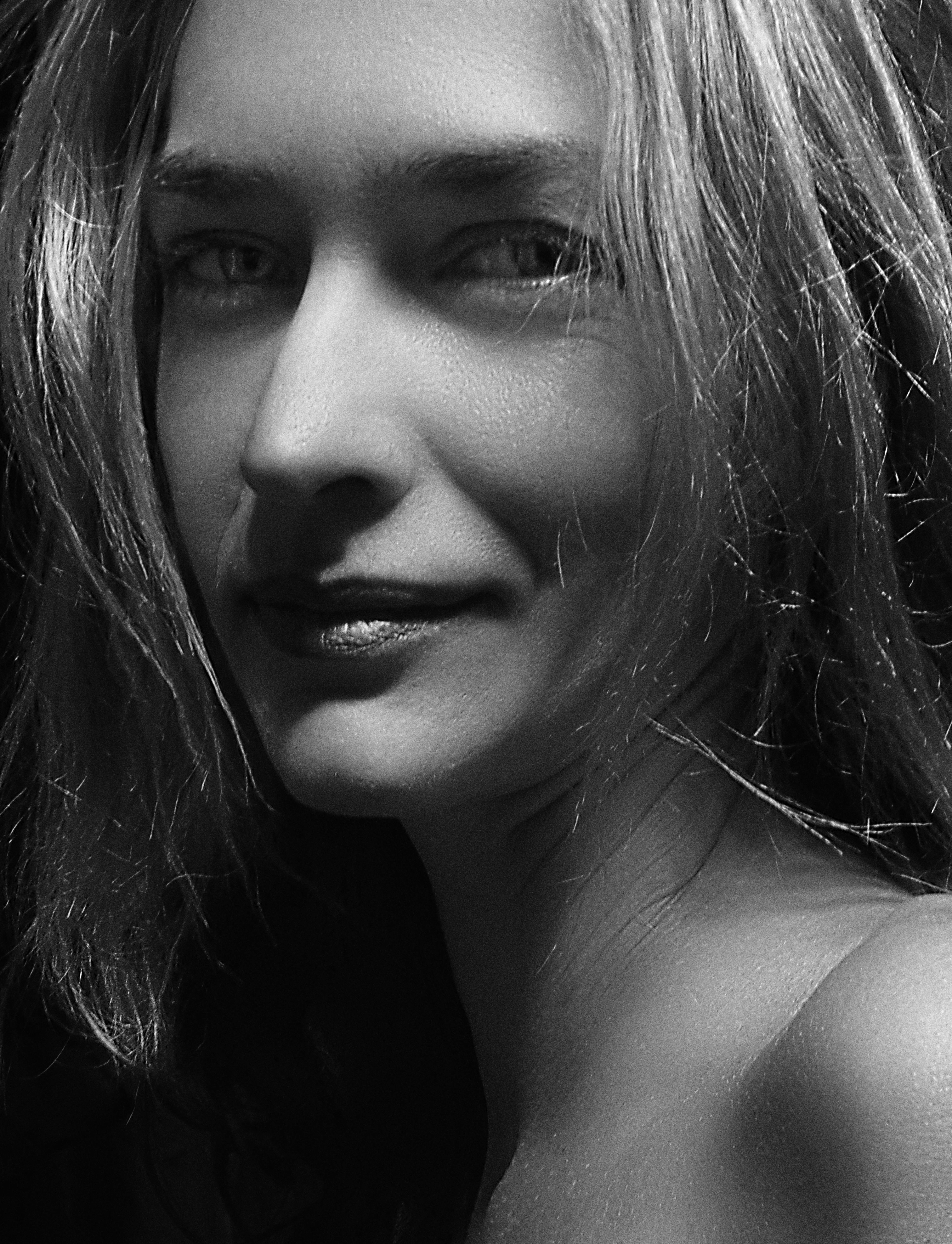 Close-up black and white portrait of a smiling woman with a soft expression.