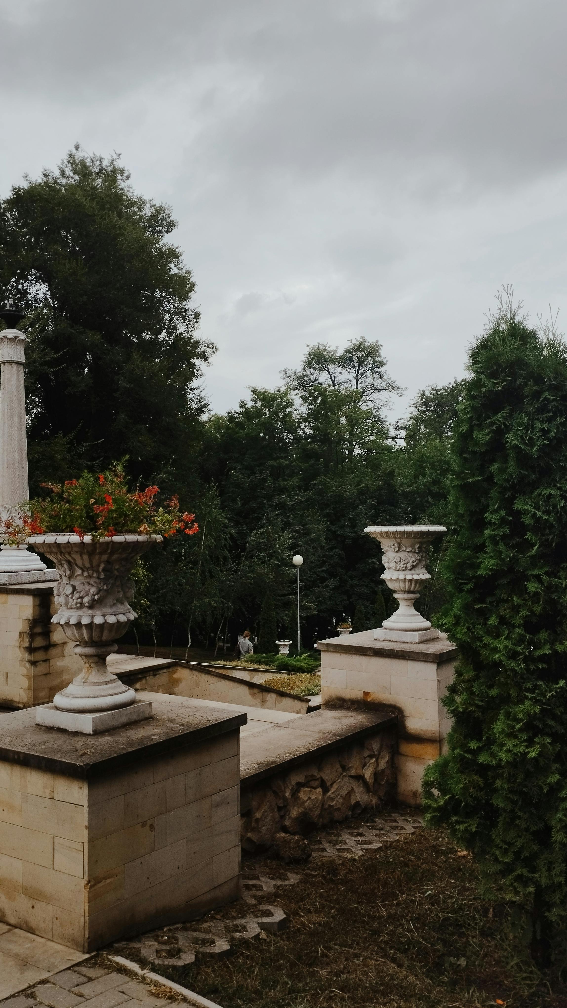 Peaceful garden scene with classical stone urns and lush greenery in Chișinău, Moldova.