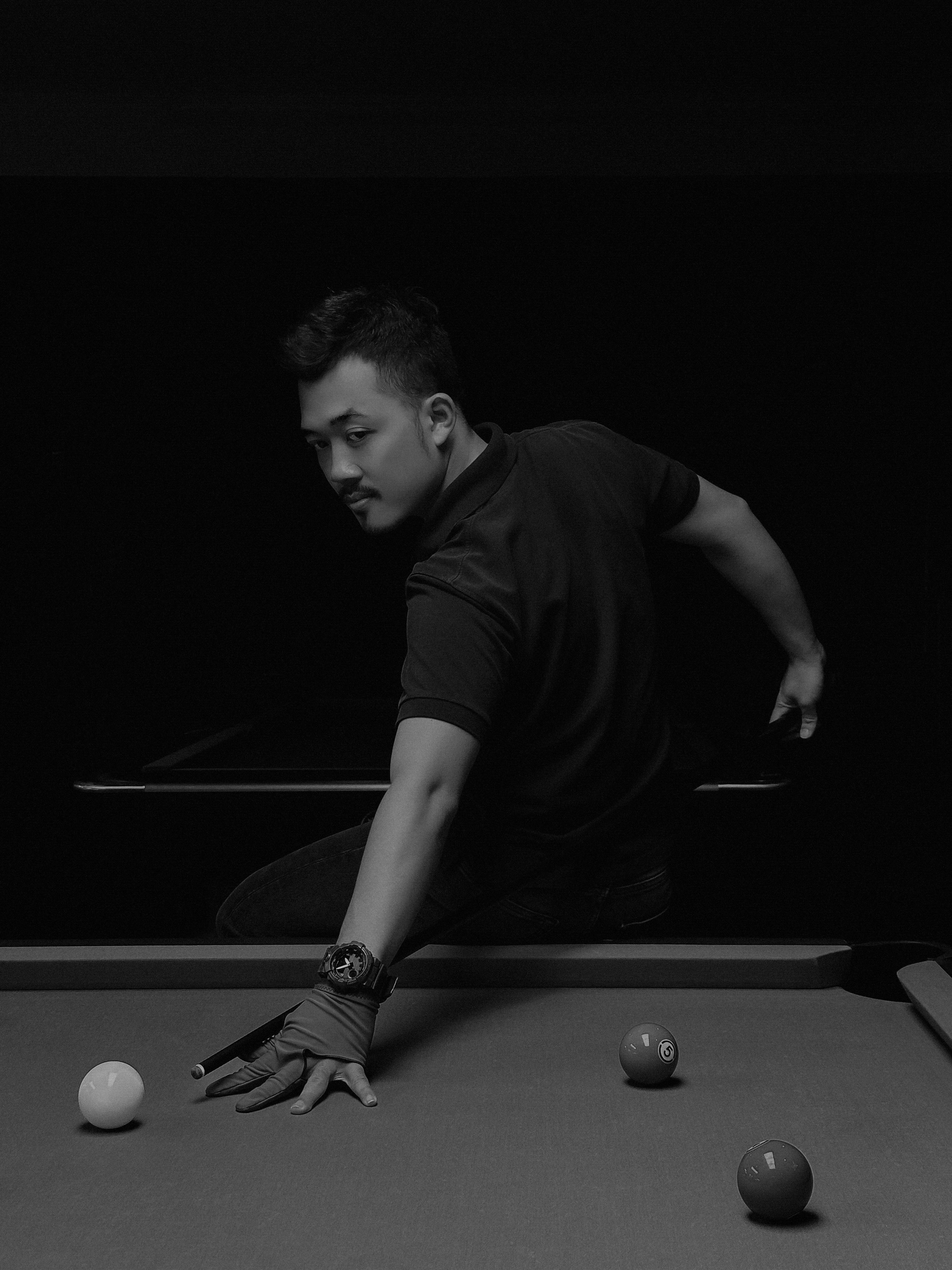 A man playing billiards in a black and white setting. Captured in Ho Chi Minh City, Vietnam.