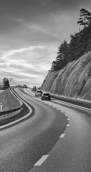 Curving highway through scenic landscape in Jönköping, Sweden with cars and rocky cliffs.