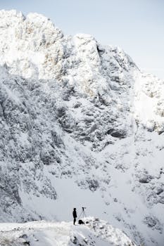 Photographer with tripod on snowy Austrian mountain slope. Winter scene.