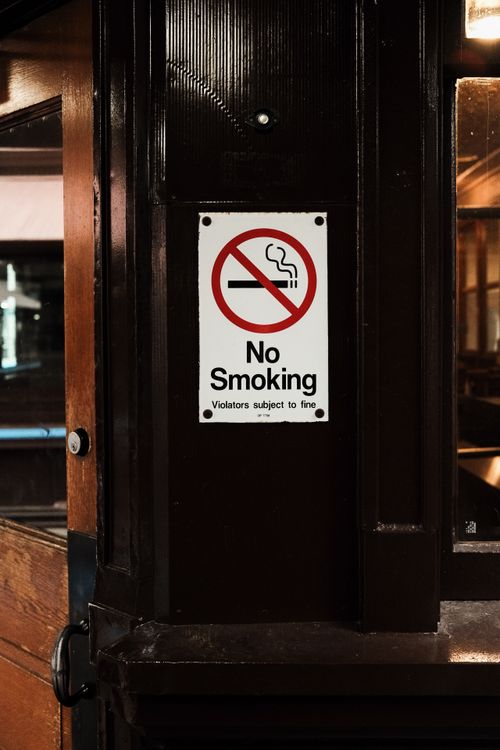Free Closeup of a no smoking sign on a wooden post indoors. Stock Photo