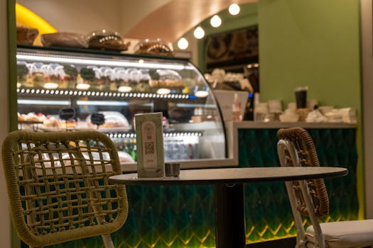 Charming cafe interior featuring empty tables and an illuminated display case filled with desserts.