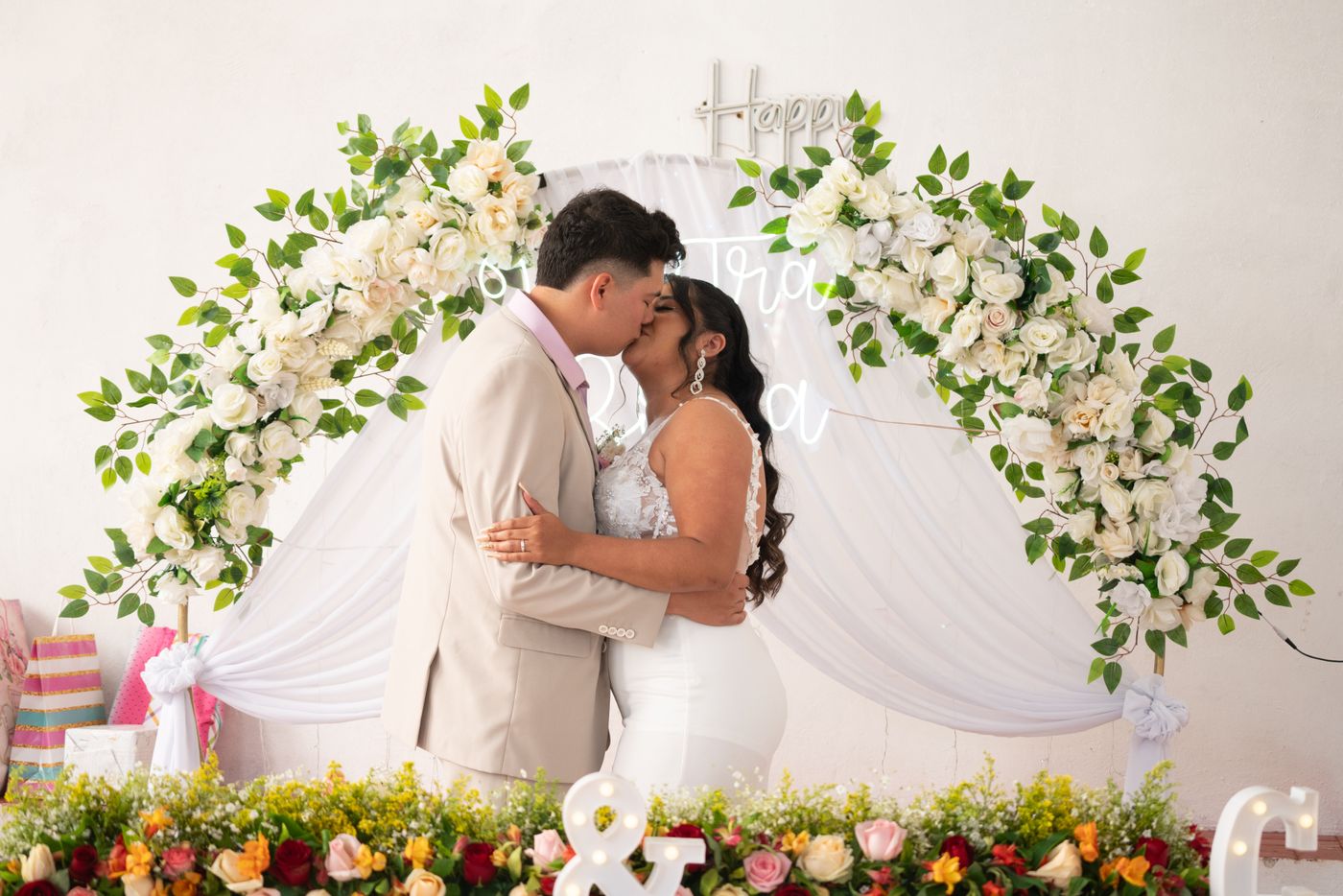 Newlyweds sharing a kiss beneath a beautiful floral wedding arch