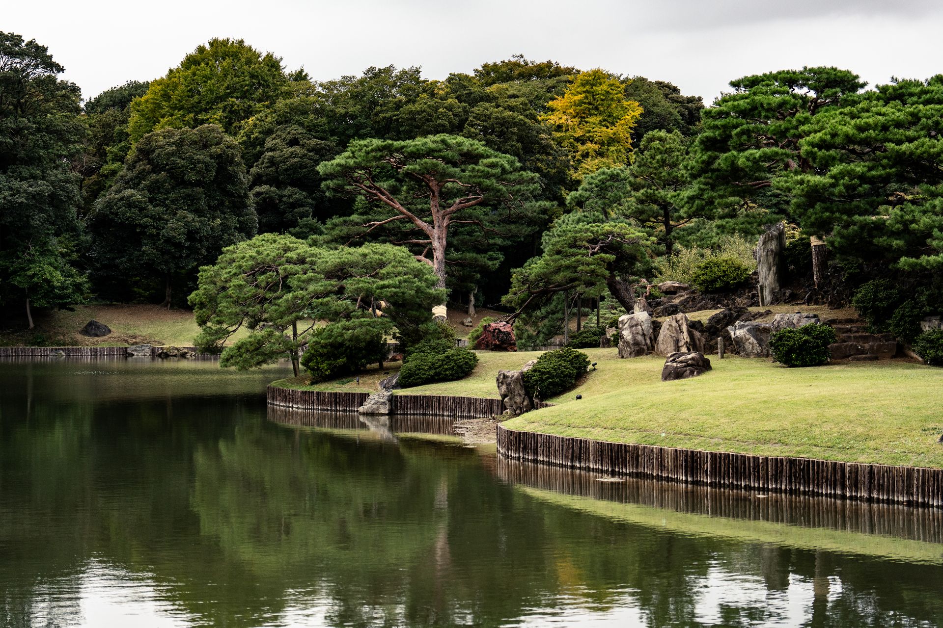 Serene Japanese garden with lush greenery and a calm reflective pond.