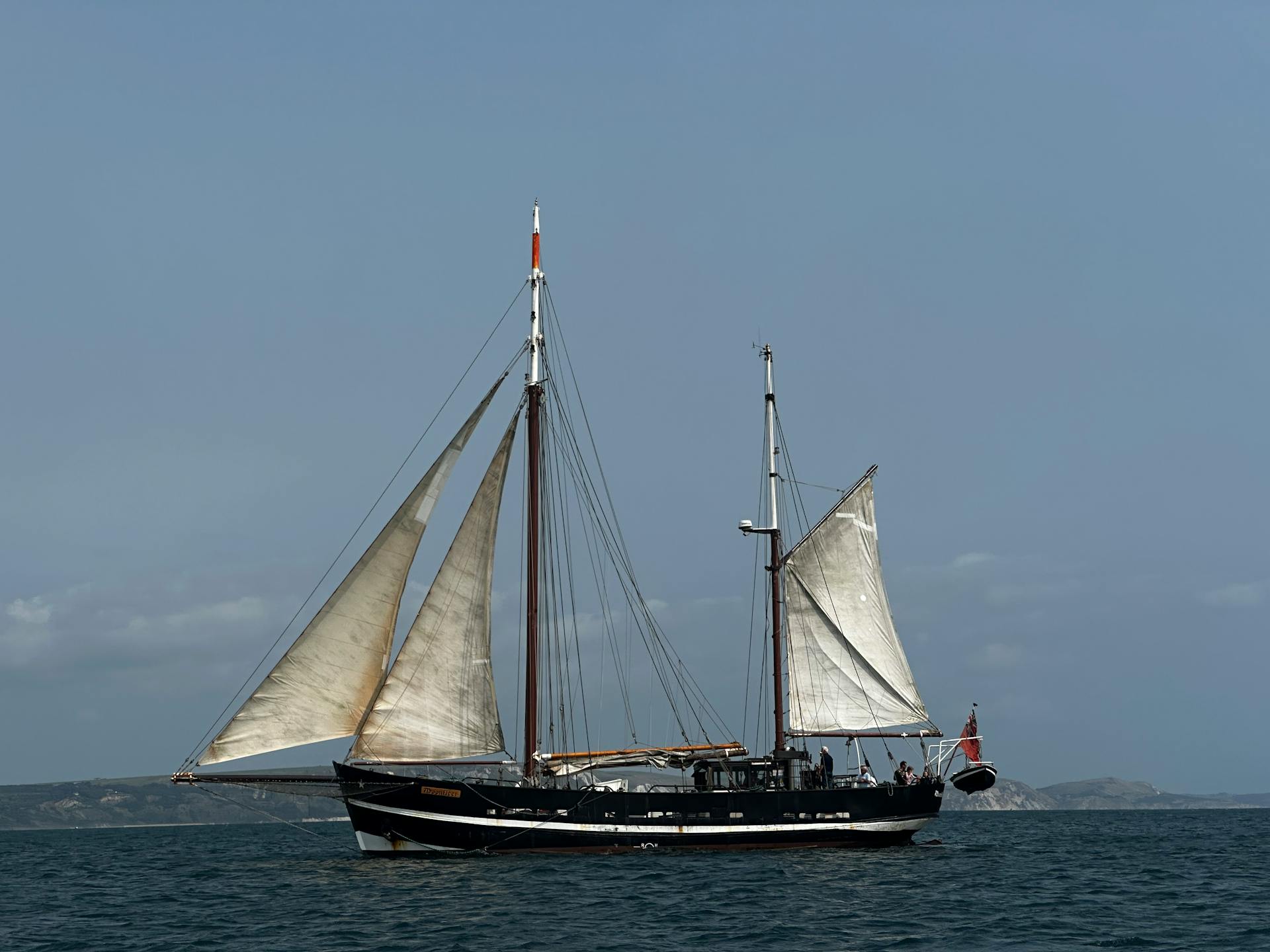 A classic sailing ship with full mast sails navigating across calm ocean waters.