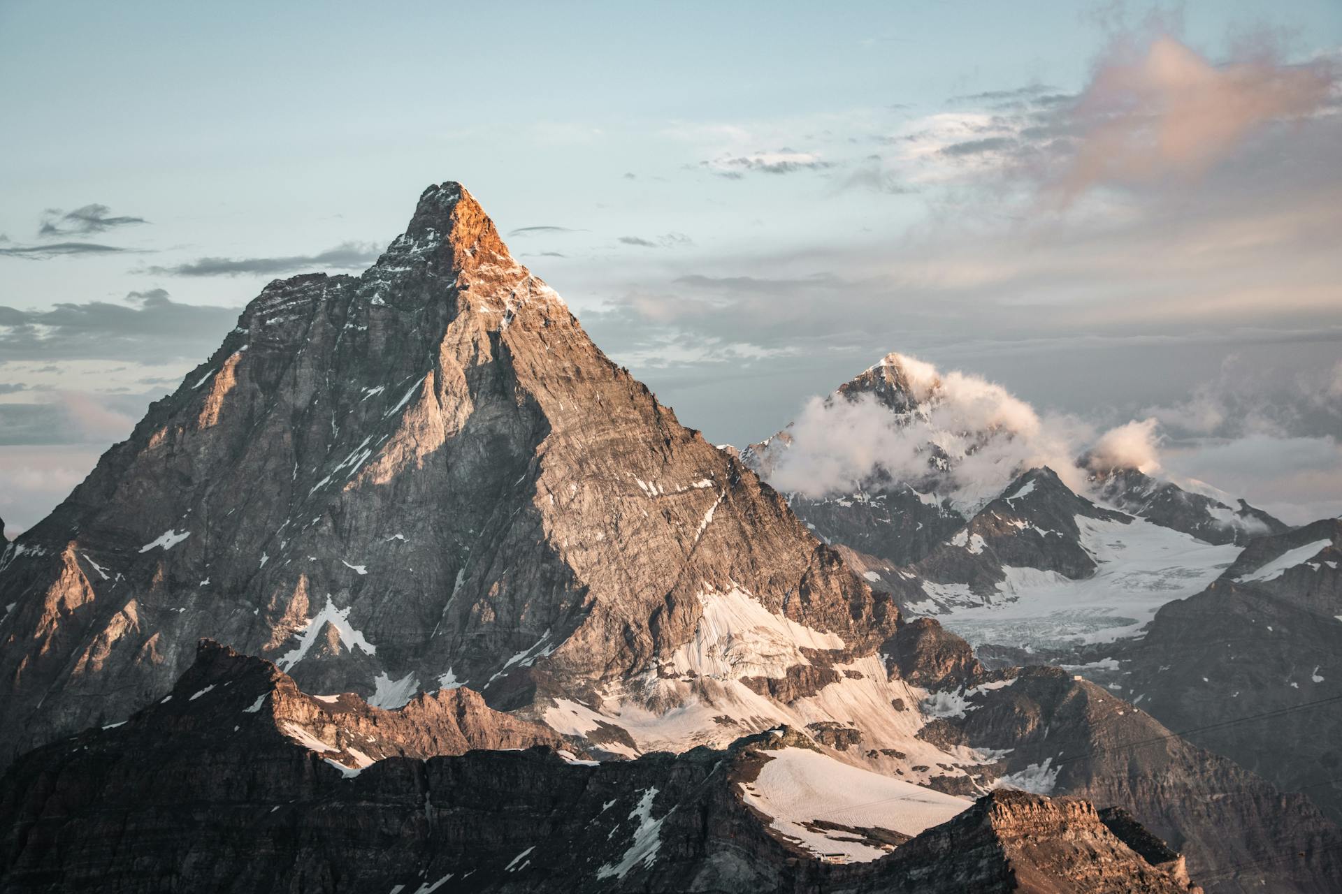 Breathtaking sunrise view of the Matterhorn in Zermatt, Switzerland, with snow-capped peaks and clouds.