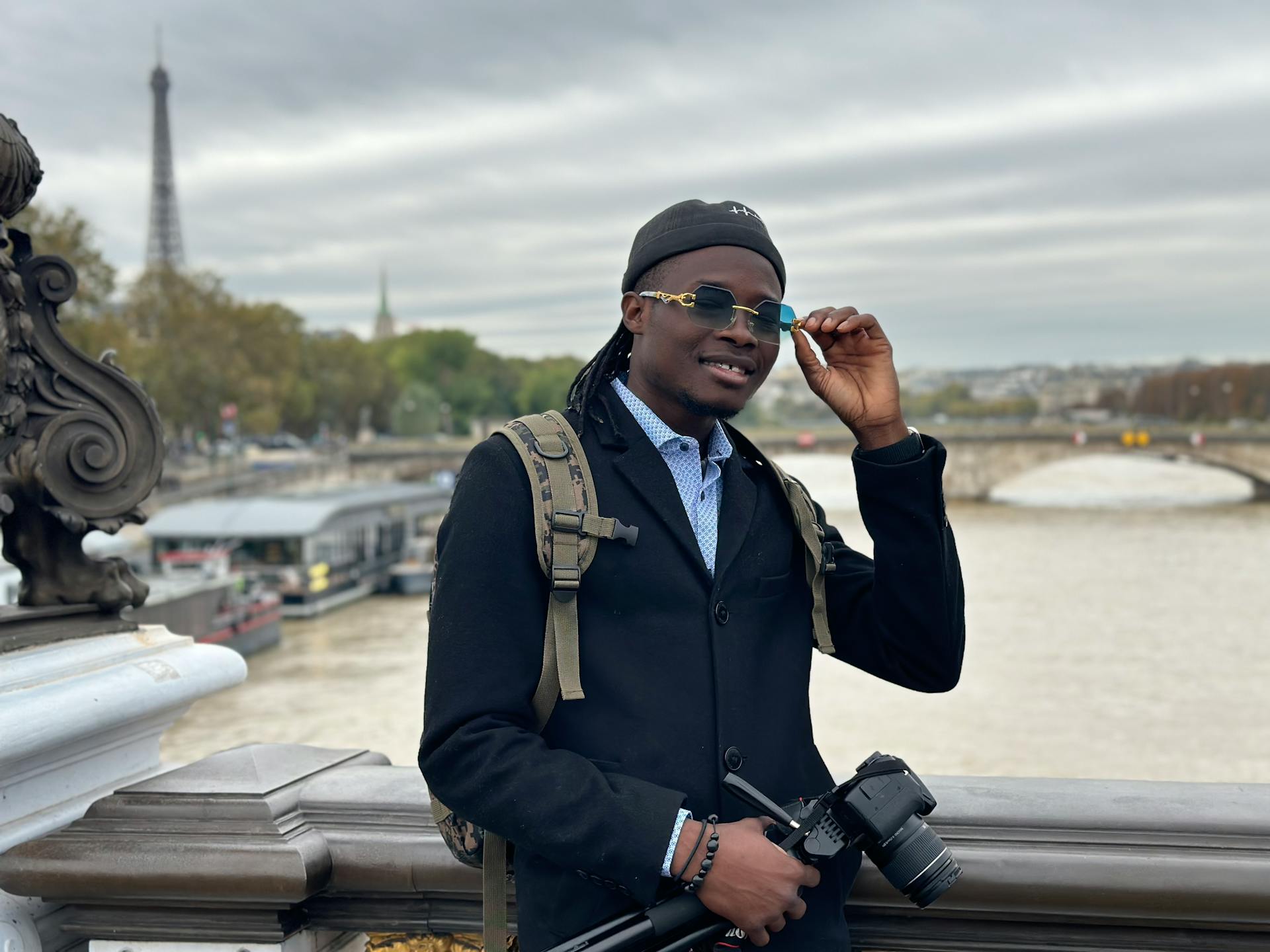 Fashionable photographer on Parisian bridge near Eiffel Tower.