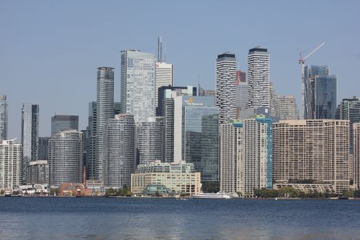 Stunning view of Toronto's iconic cityscape reflected across the calm lake on a sunny day.