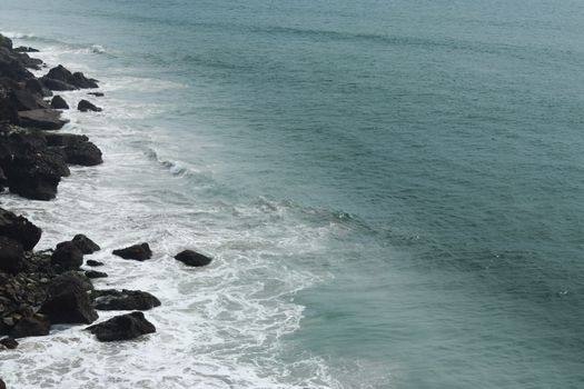 Stunning aerial shot of Kerala's rocky coastline with waves crashing against the shore.