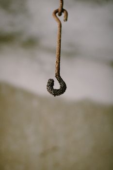 Detailed view of a rusty and weathered metal hook with texture and patina.