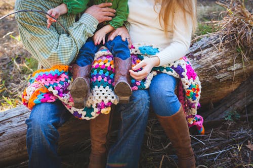 Free Toddler Sitting on Person's Lap While Person Sitting Also on Tree Trunk Stock Photo