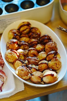 Freshly made takoyaki drizzled with sauce, served in an oval dish, perfect for Japanese cuisine lovers.
