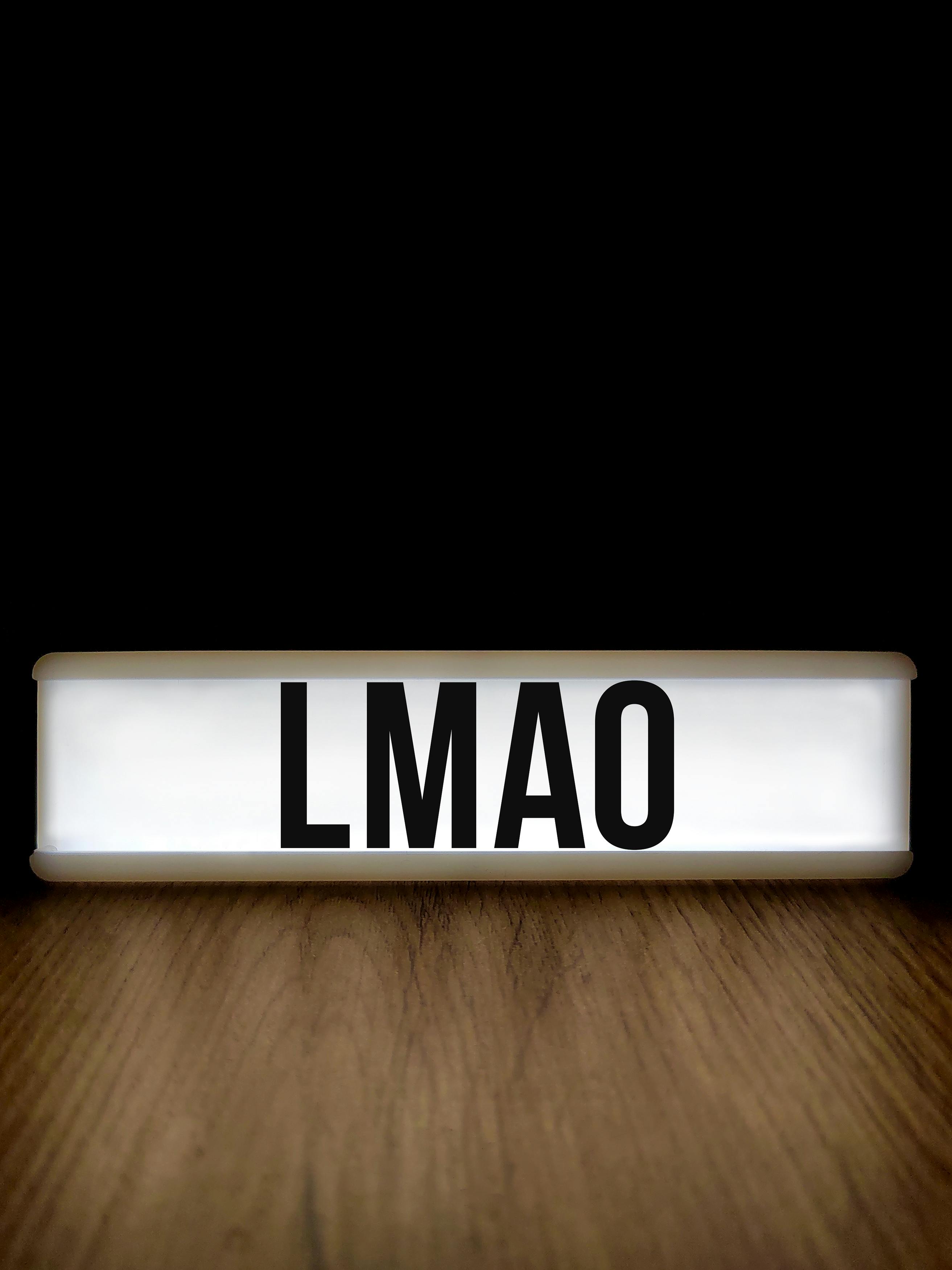 De franc Un rètol humorístic de caixa de llum que mostra el popular argot de text "LMAO" sobre una superfície de fusta. Foto d'estoc