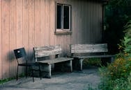 Two Gray Wooden Benches and Black Metal Armless Chair Beside Wall