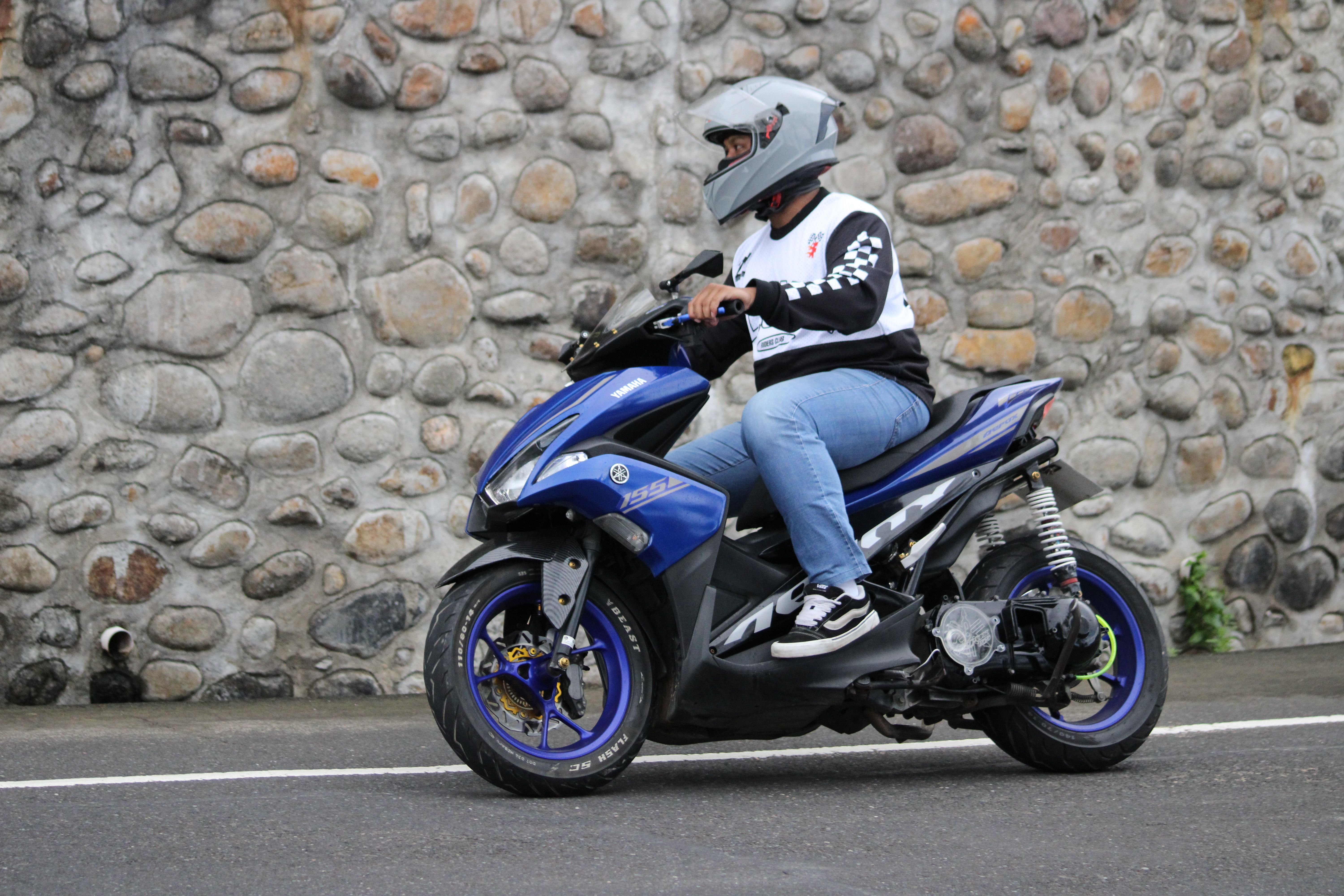 Man Riding Blue Scooter Against Stone Wall · Free Stock Photo