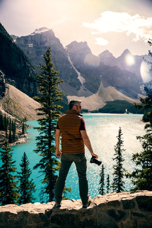Free Man Standing on a Stonewall looking at the Mountains and Body of Water Stock Photo