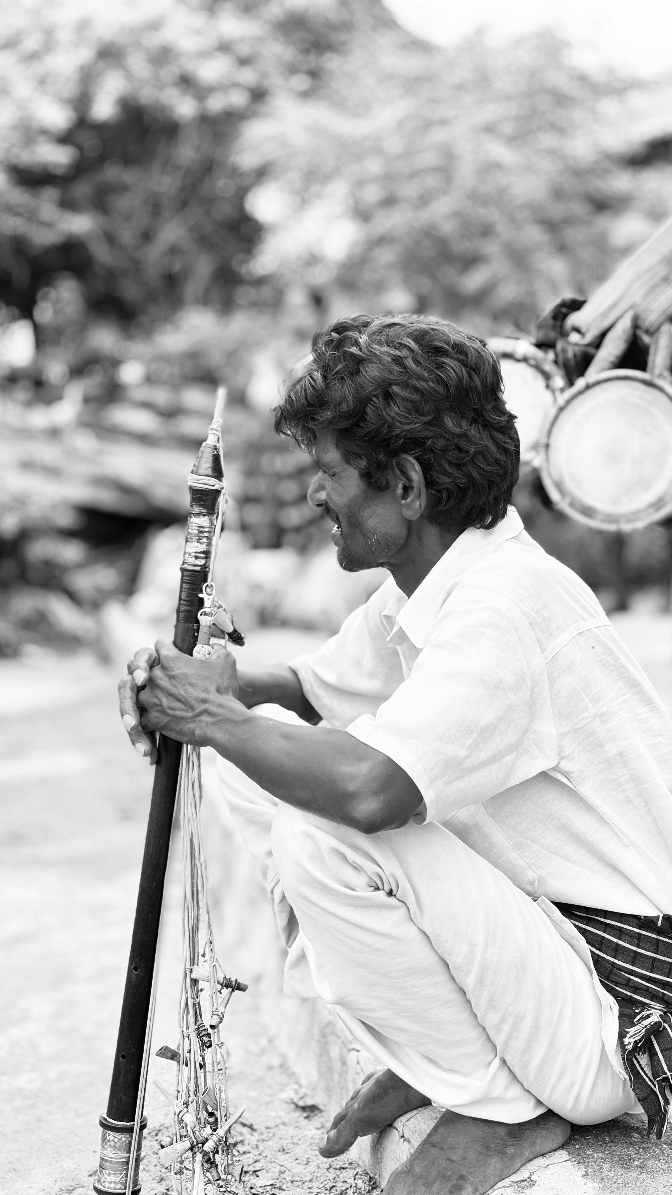 Black and white portrait of a street musician playing a traditional instrument outdoors.