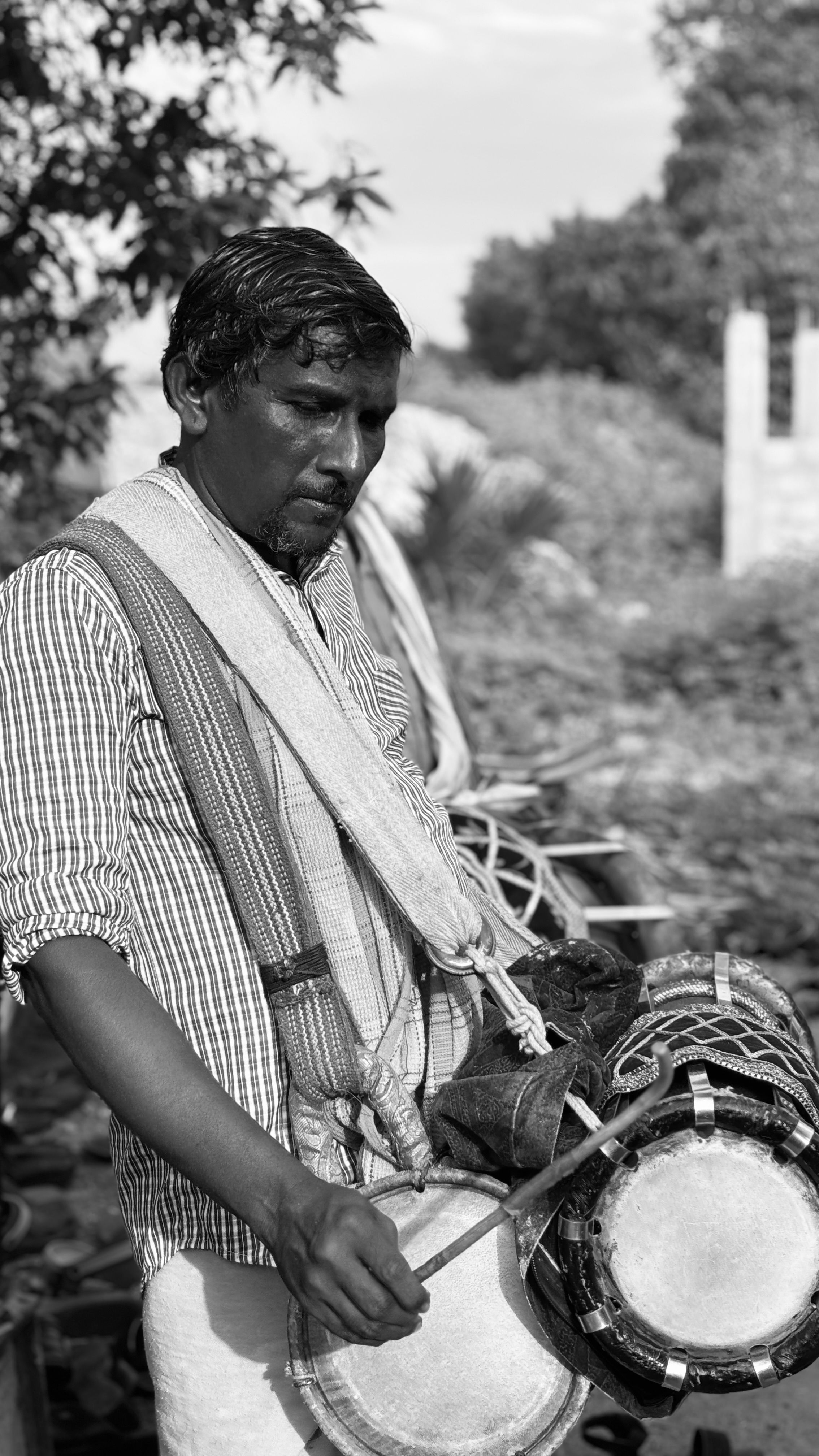 Black and white portrait of a drummer playing tribal drums outdoors.
