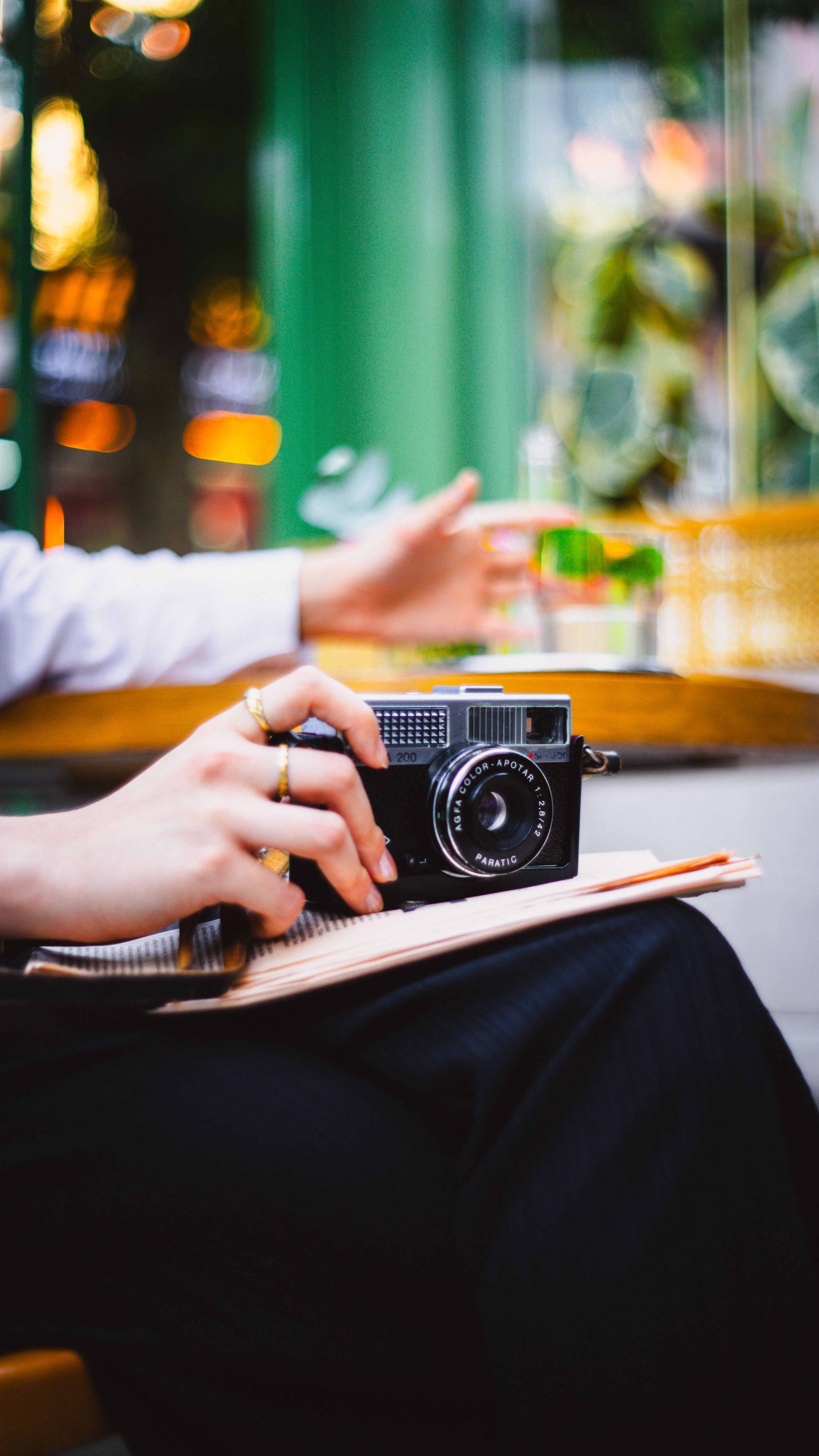 A close-up of hands holding a vintage camera in a trendy cafe.