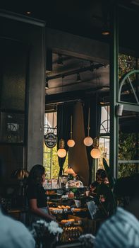 Modern cafe interior with pendant lights and people enjoying coffee.