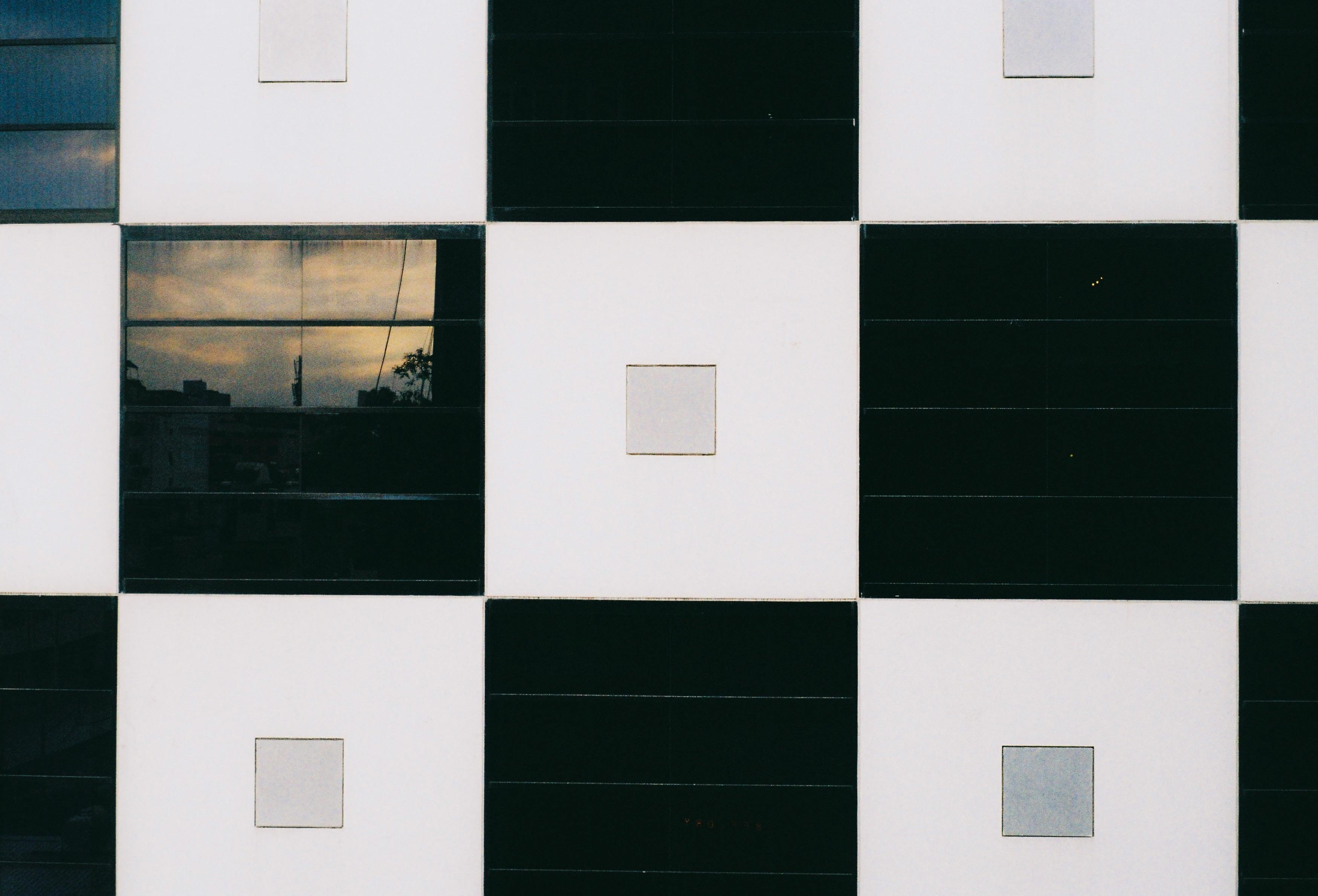 Gratis Nærbillede af en moderne bygningsfacade med skakternet mønster og byrefleksion. Lagerfoto