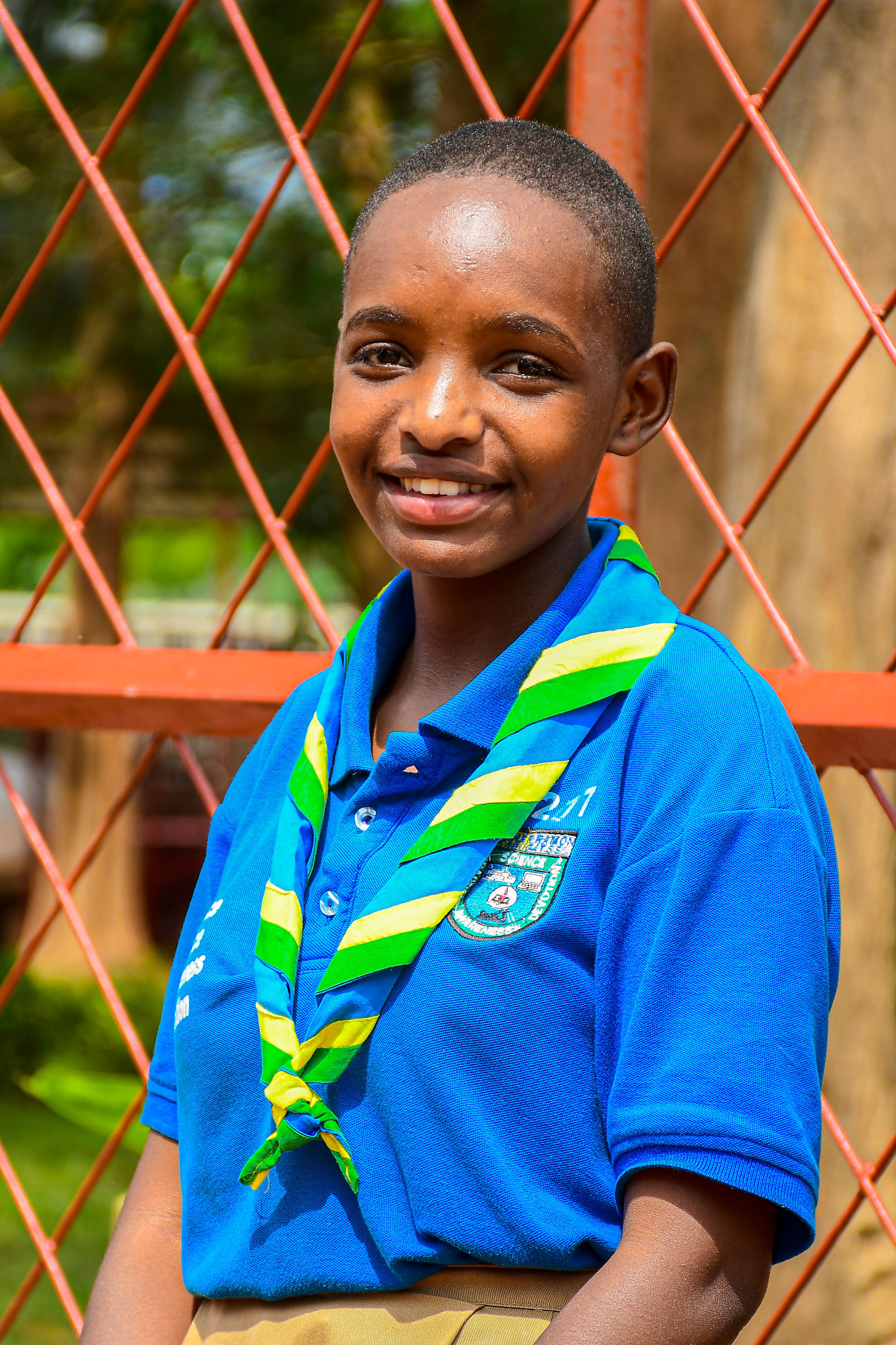 A young scout in a blue uniform poses outdoors in Southern Province, Rwanda.