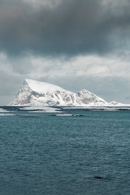 Free A striking snowy mountain in the Arctic with dramatic cloudy skies. Stock Photo
