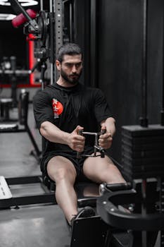 Man concentrating while using a rowing machine in a modern gym.