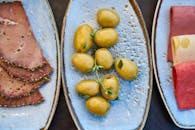 陶瓷盘上盛放着橄榄、冷盘和奶酪的乡村熟食盘顶视图