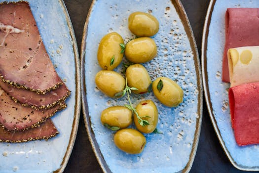 陶瓷盘上盛放着橄榄、冷盘和奶酪的乡村熟食盘顶视图