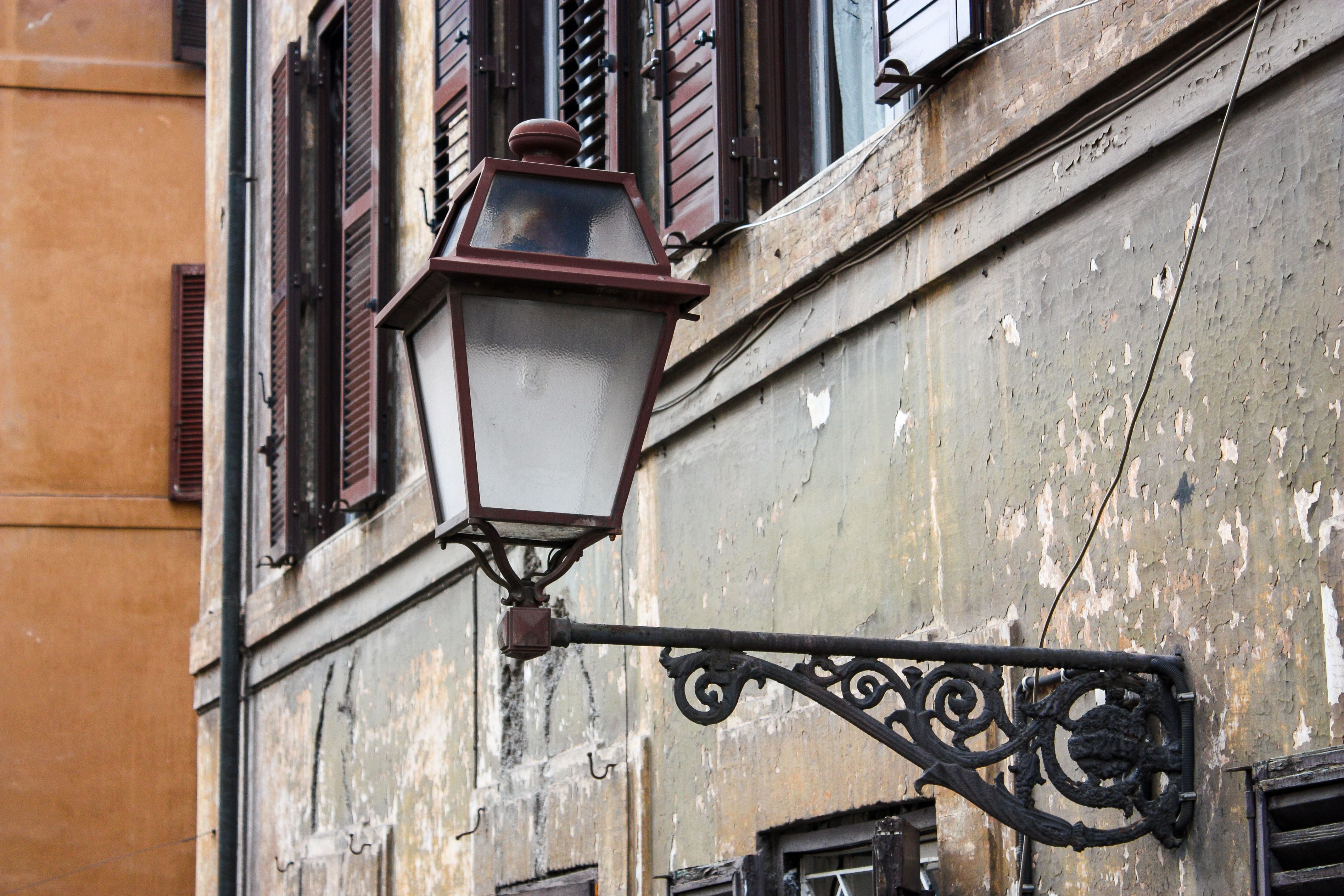 Bezpłatne Rustykalna latarnia uliczna na starej fasadzie w Rzymie, oddająca urok historycznej architektury. Zdjęcie z galerii