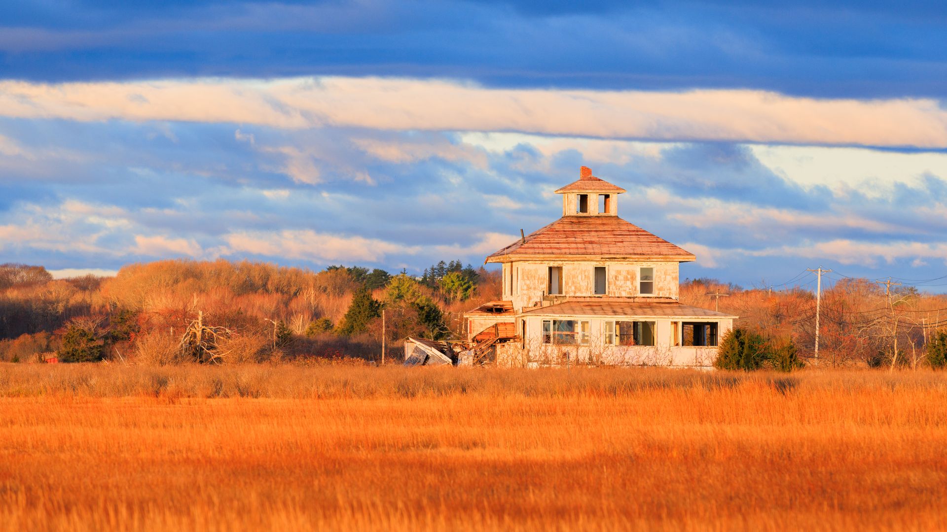 Charming rustic house in Newbury, Massachusetts with vibrant fall colors, under a dramatic sky.