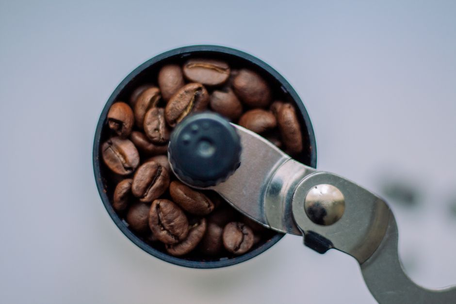 Close-up of roasted coffee beans in a manual grinder shot from above.