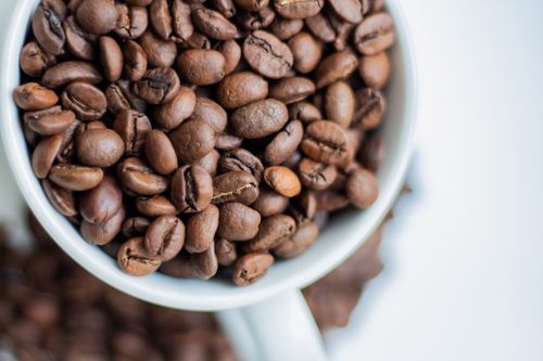 Free A detailed shot showing roasted coffee beans in a white cup. Stock Photo