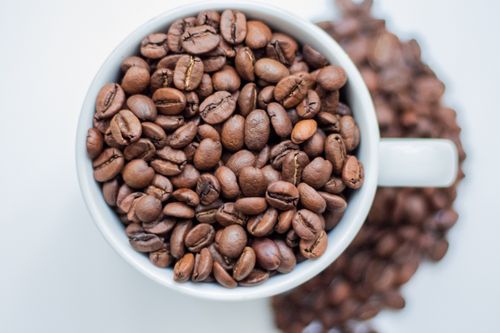 Free Top view of roasted coffee beans in a white cup, isolated on white. Stock Photo