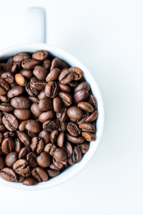 Free High angle view of roasted coffee beans in a white cup on a clean background. Stock Photo