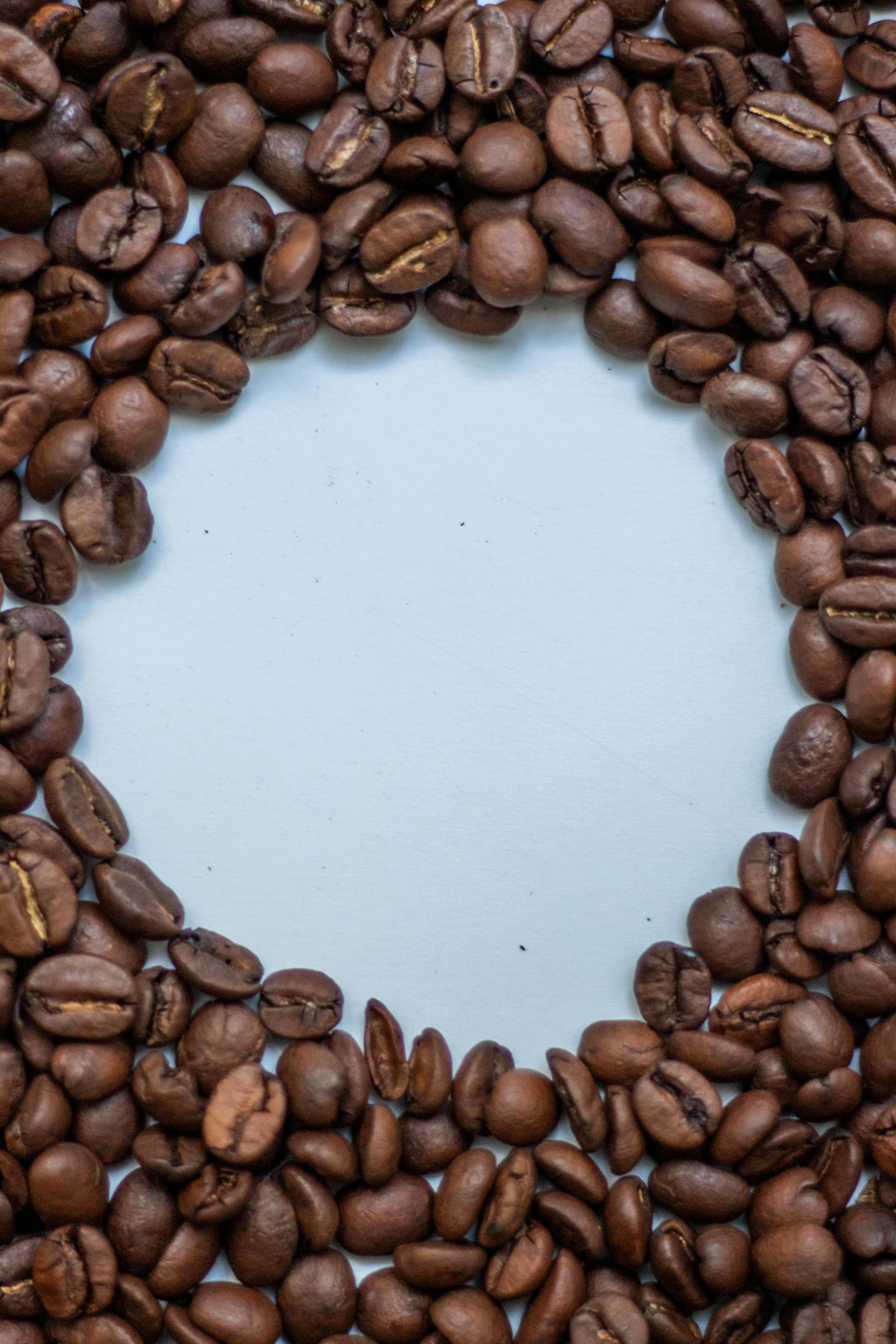 Round arrangement of coffee beans with copyspace on a blue surface, perfect for design use.