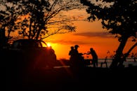 在印度尼西亚万纳多，充满活力的日落映衬着人和汽车的剪影