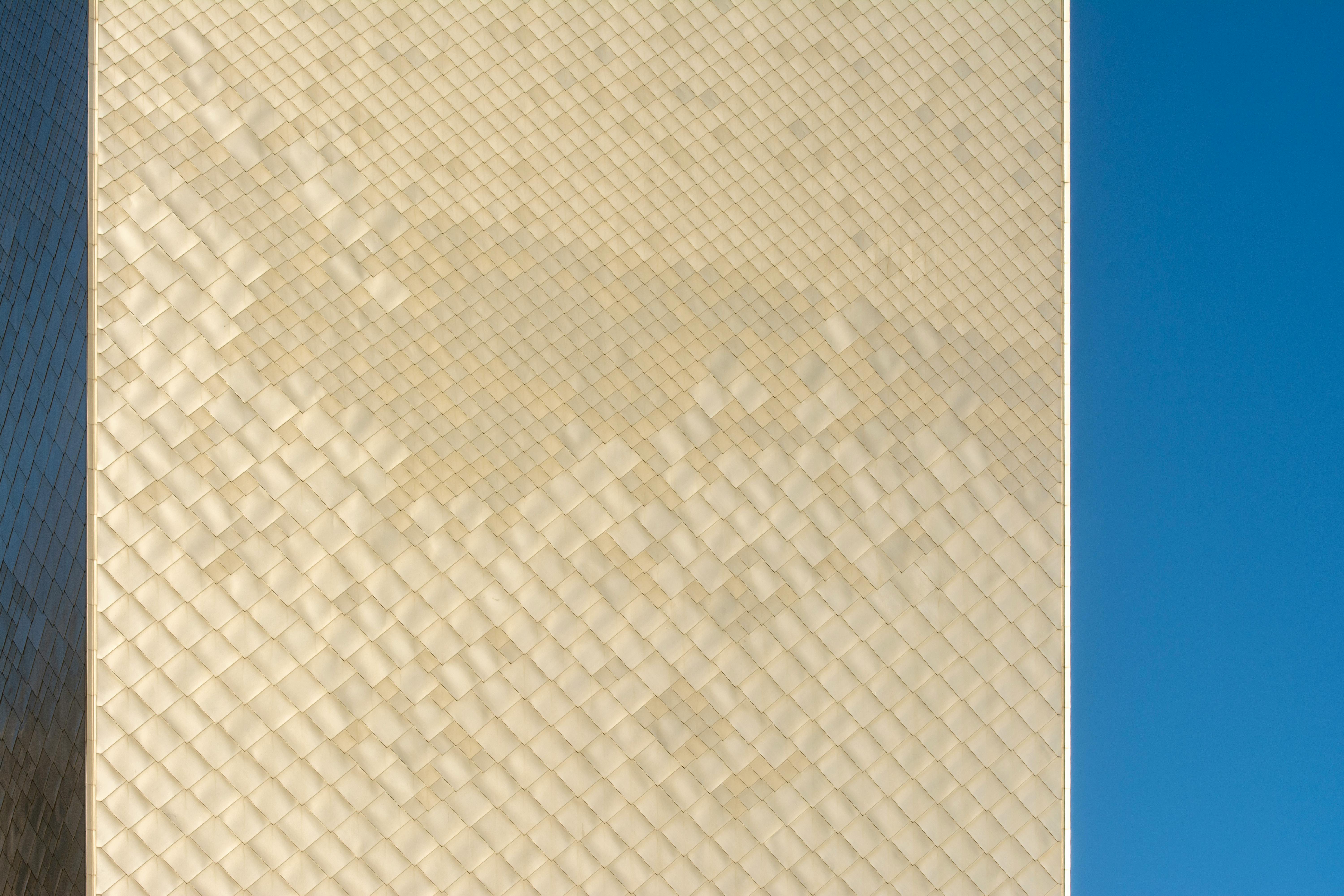 ingyenes Közeli kép egy geometrikus építészeti homlokzatról a tiszta kék égen, modern dizájnt mutatva be. Stockfotó