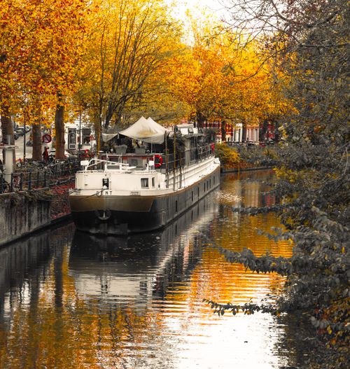 Free Serene autumn canal in Ghent with a boat reflecting vibrant fall colors. Stock Photo