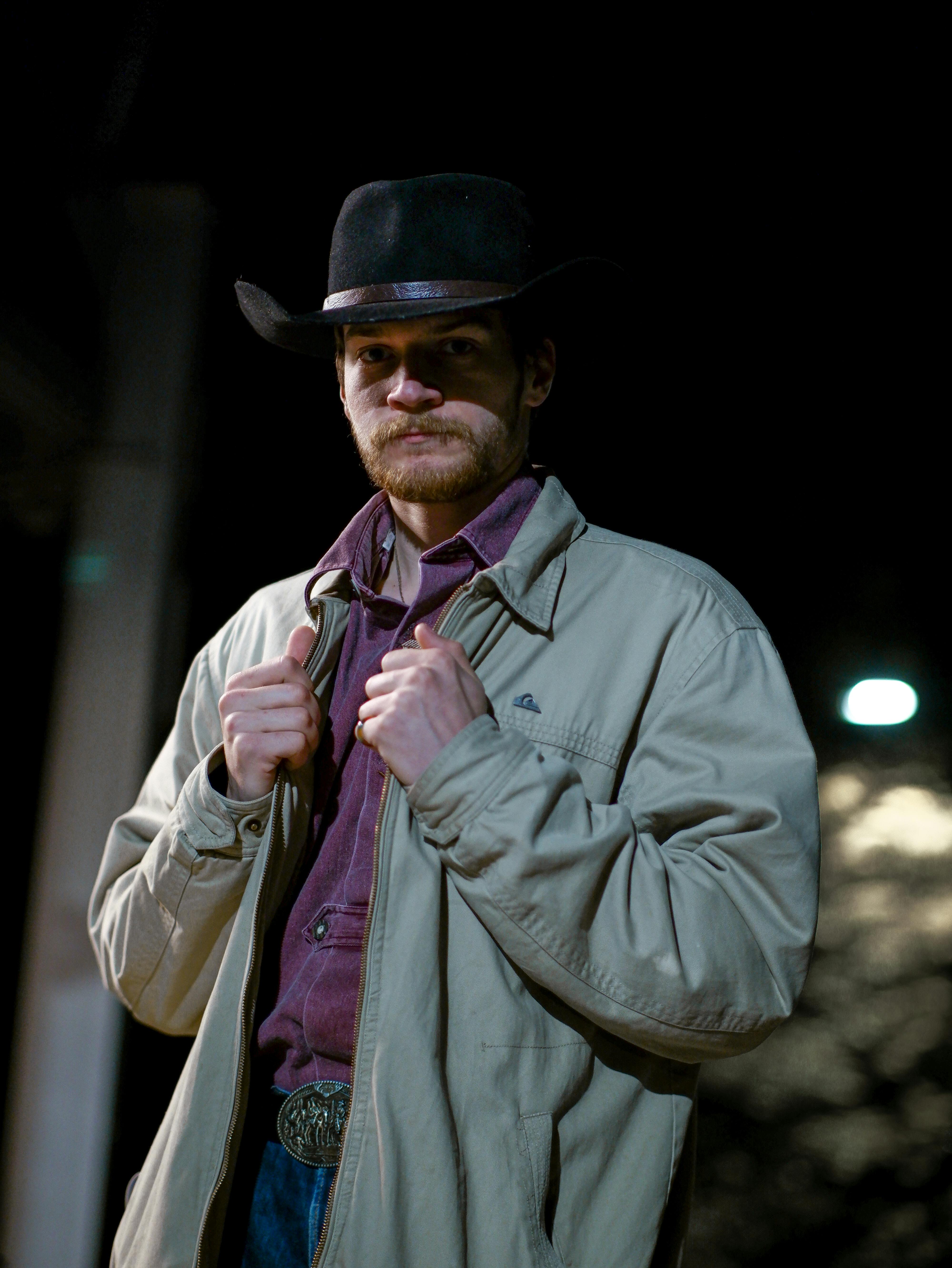 Man in western attire poses at night in Bratislava. Urban cowboy theme.