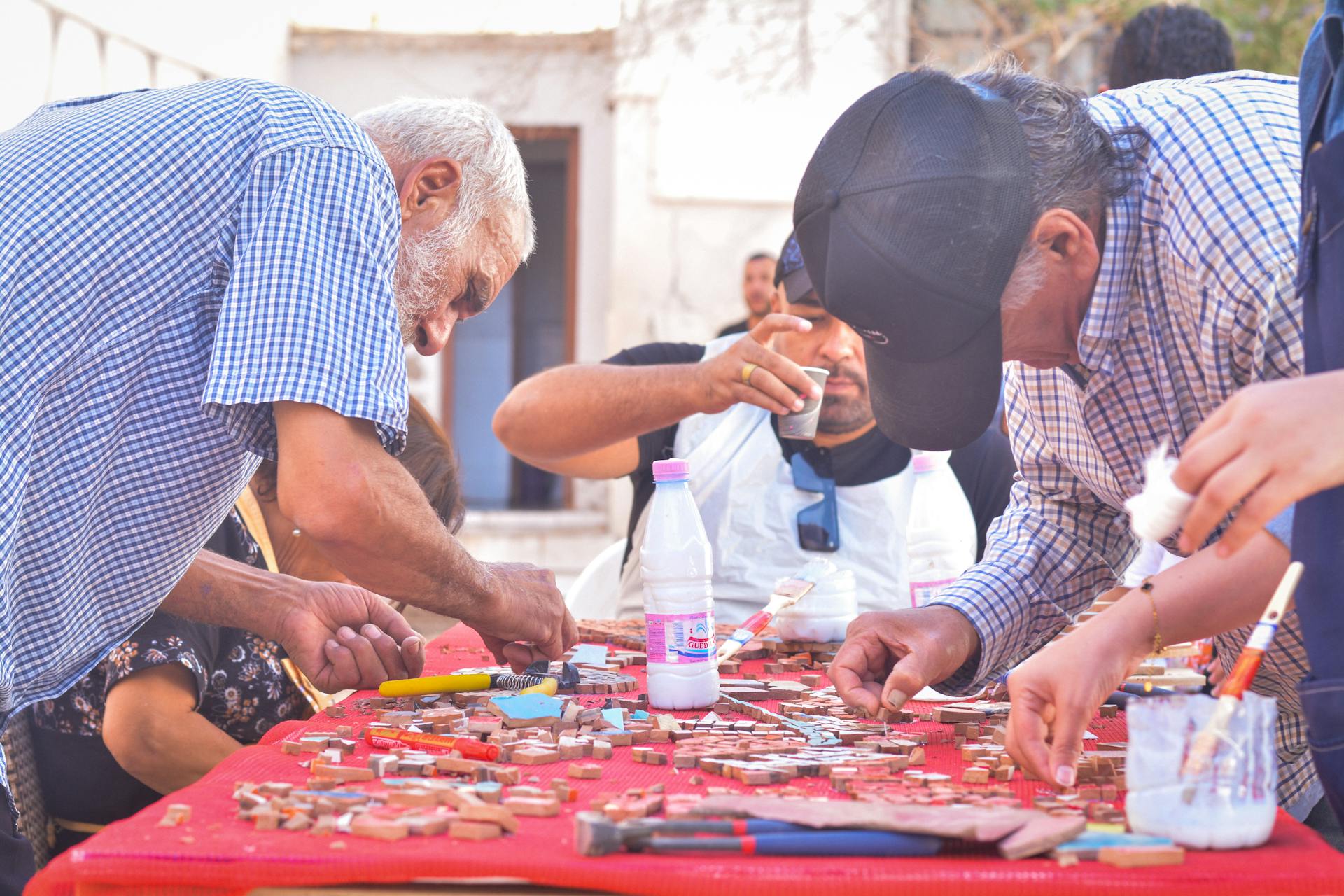 Adults gathered outside working on collaborative art project, focusing intently.