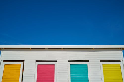 Maison En Bois Blanc Avec Fenêtres Peintes En Jaune, Rose, Vert Et Orange