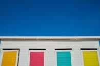 一个充满活力的海滩小屋，其门上装饰着五颜六色，与清晰的蓝天形成鲜明对比