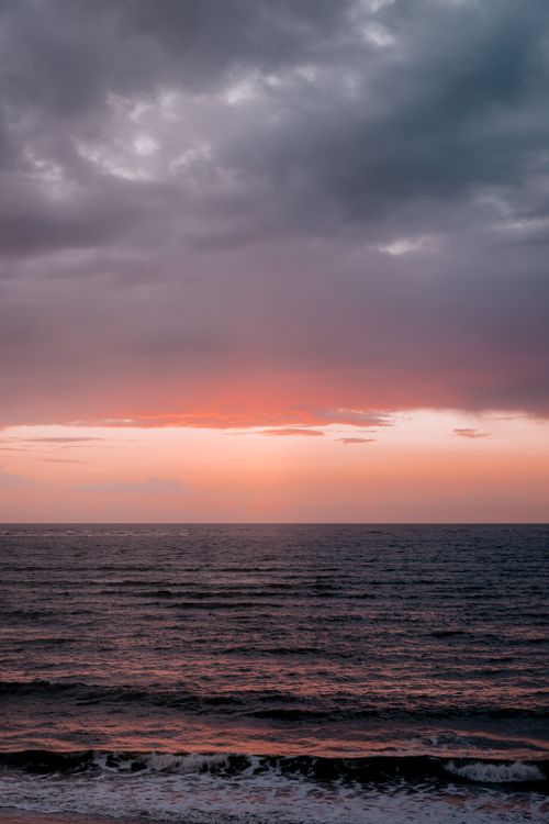 Free A peaceful ocean sunset with vibrant colors and dramatic clouds on the horizon. Stock Photo