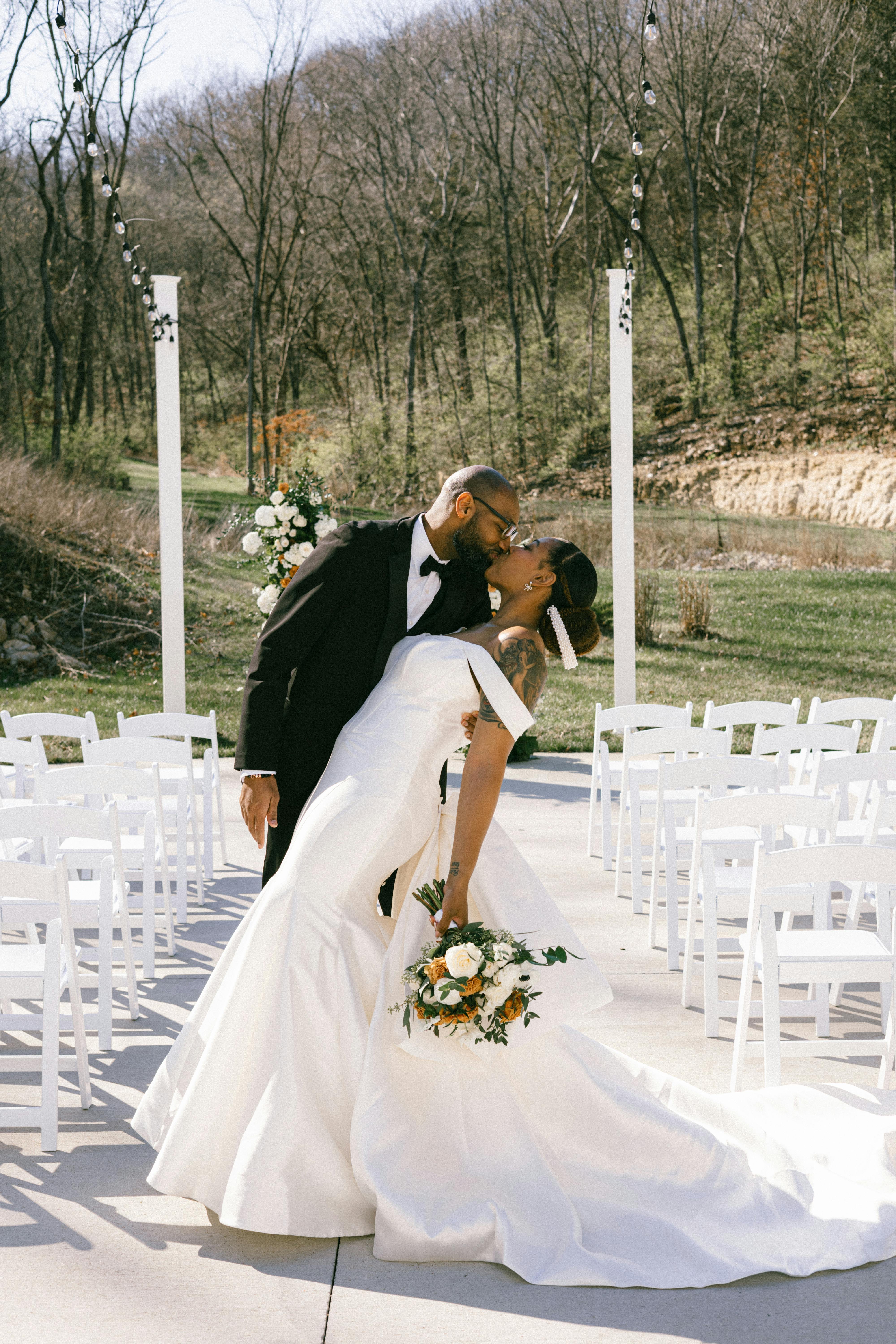 Elegant couple sharing a romantic kiss during their outdoor wedding ceremony.
