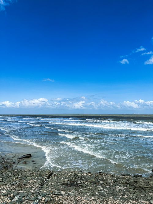 Free Waves crashing on a rocky beach under a bright blue sky in São Luís, Brazil. Stock Photo
